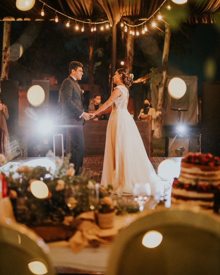 A couple dancing beneath strings of lights at an evening reception