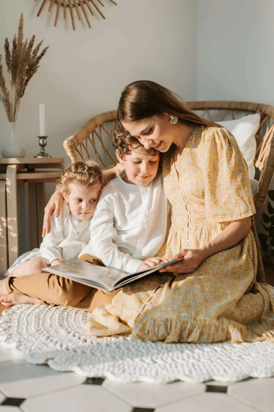 A mother and two children sitting on the floor looking through a photo book together