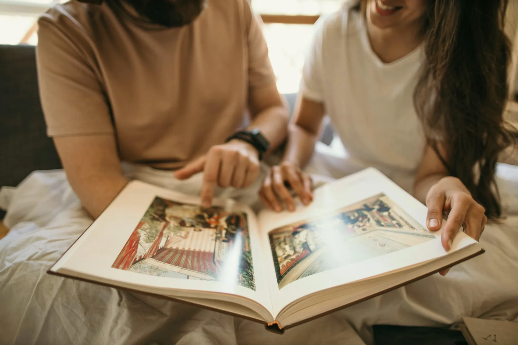 Two people sitting together turning the pages of an old family photo album