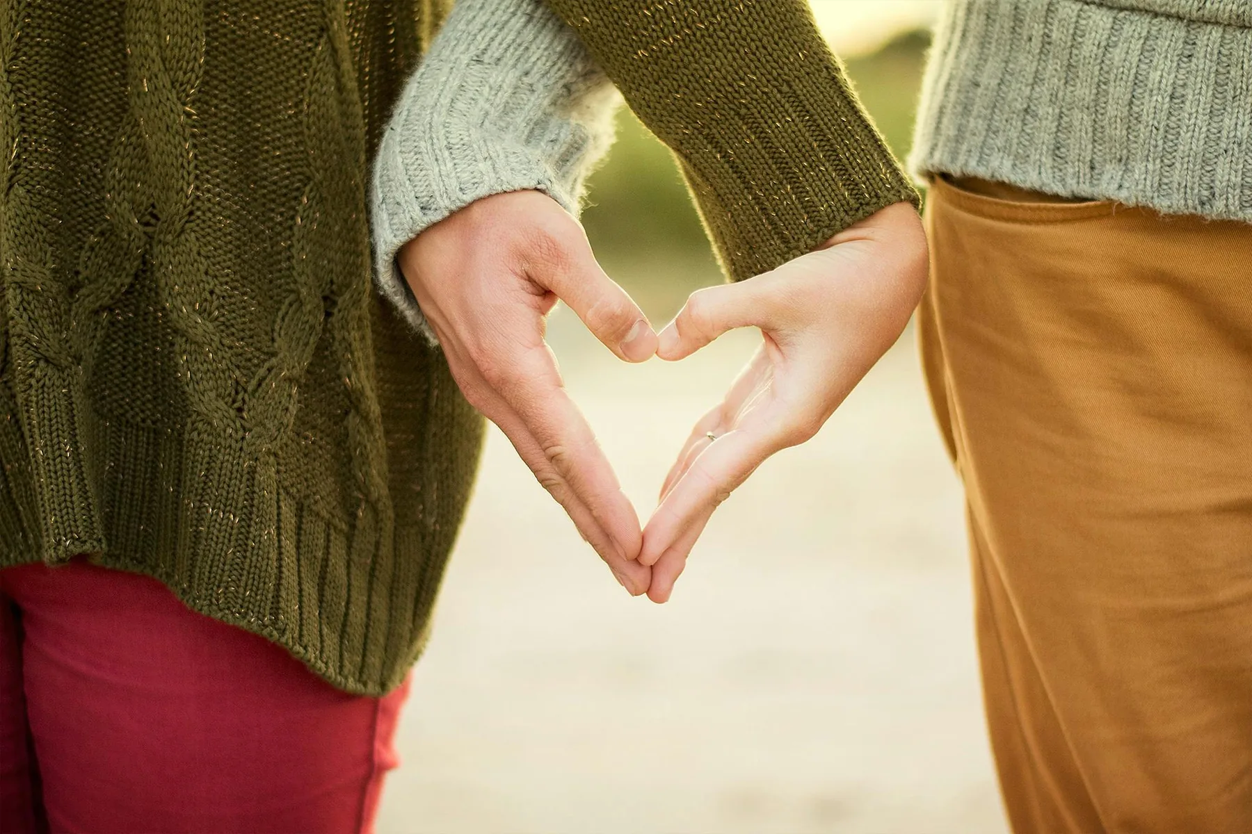Two people's hands forming a heart shape between them