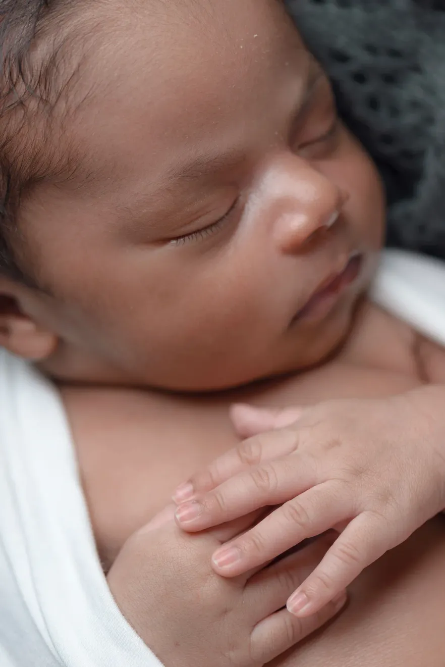 A sleeping newborn with one hand curled up beside their face
